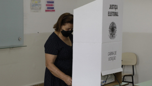 Pessoa votando de máscara em uma urna eleitoral